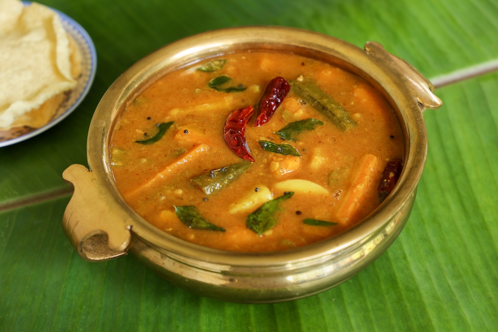 Kadamba sambar with lot of vegetables in a pot above green banana leaf